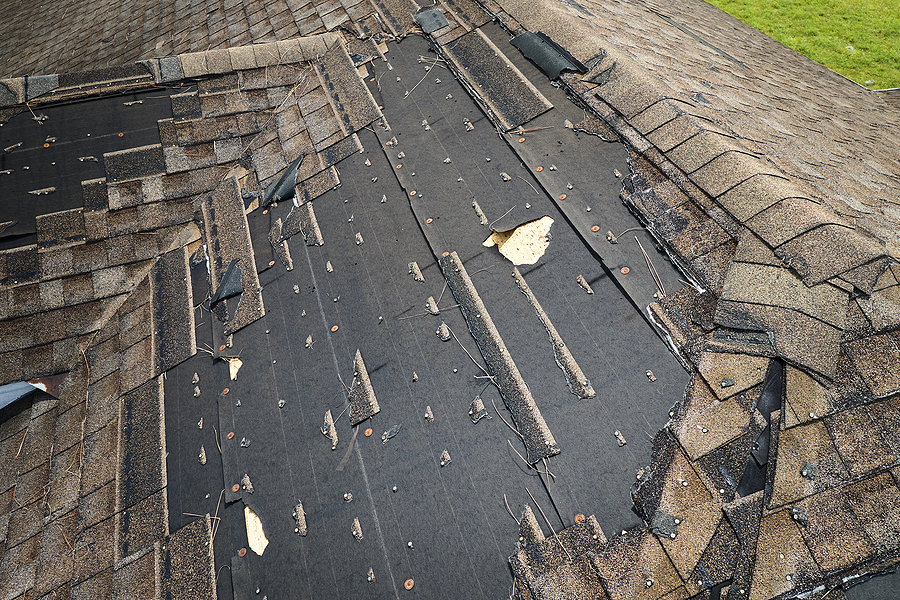 Damaged House Roof With Missing Shingles After Hurricane Ian In
